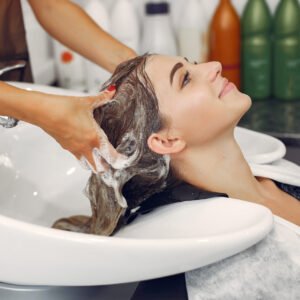 Hairdresser washing head her client. Woman in a hair salon